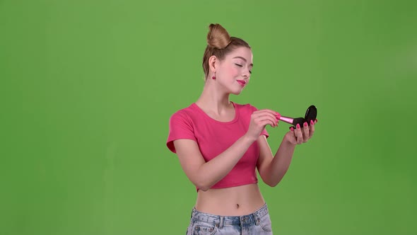 Teen Girl Holding a Brush in Her Hand and Powdering Her Face. Green Screen. Slow Motion