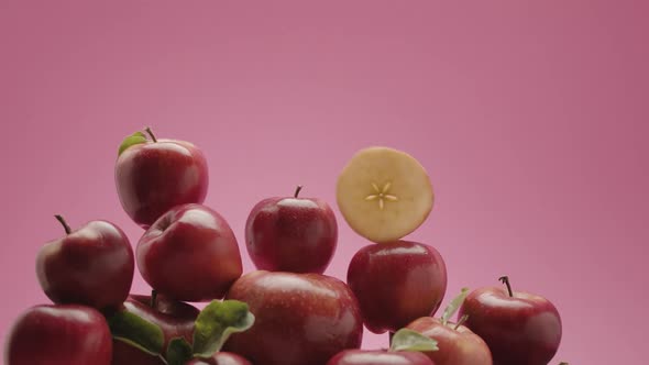 Many Red Apples and a Slice Slowly Descend Over the Apples Redpink Background