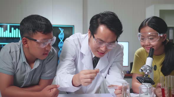 Asian Boy And Girl Learning Science Experiment In Laboratory With Teacher In Classroom alt