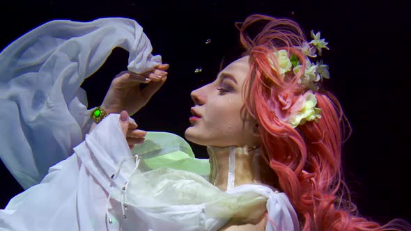 Fairytale Mermaid Is Looking Up and Playing with Her Dress Floating Underwater