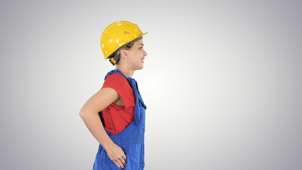 Young Woman in Yellow Hardhat Walking on Gradient Background