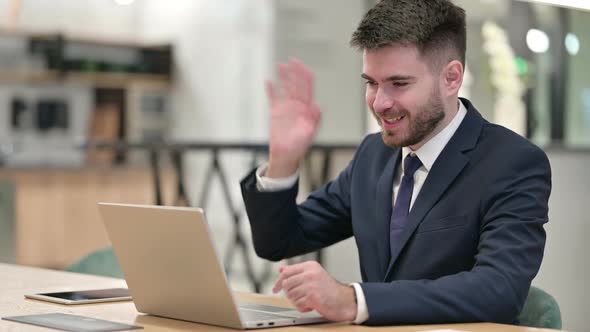 Cheerful Young Businessman Talking on Video Call on Laptop in Office