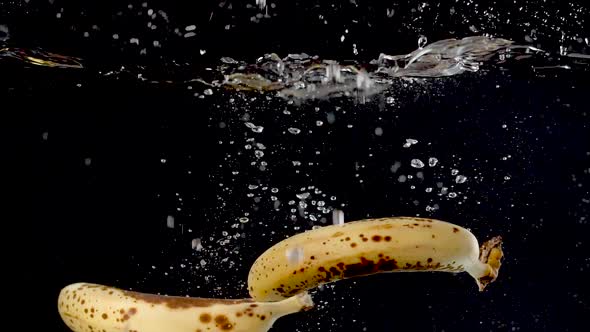 Ripe bananas being dropped into water in slow motion.