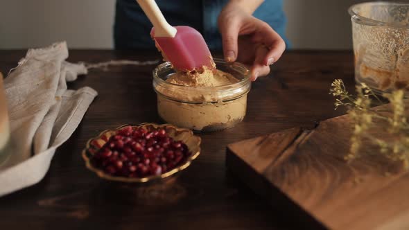 A Girl Using a Kitchen Silicone Spatula Flatten Out Cooked Healthy Homemade Hummus in a Glass Bowl