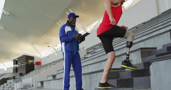 Diverse male coach and disabled athlete with prosthetic leg training, running up stairs