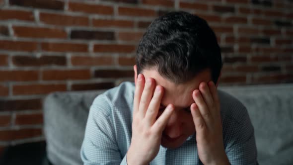 Close portrait sad stressed 30s man person sitting at home and looking side by side