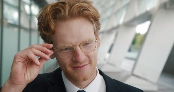 Close Up Portrait of Smiling Redheaded Businessman in Eyeglasses Wearing Classical Suit Standing
