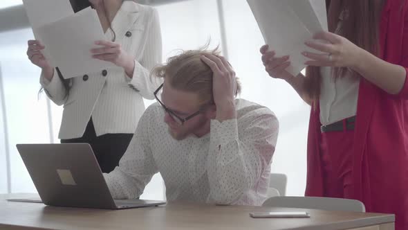 Tired Stressed Man Sitting in a Comfortable Office with Netbook at the Table Signing Documents Which