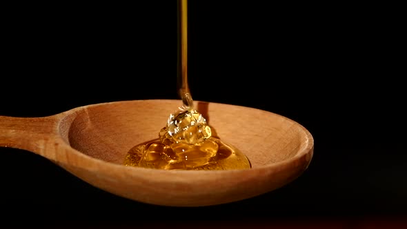 Honey Dripping From a Wooden Honey Dipper on Black, Slow Motion