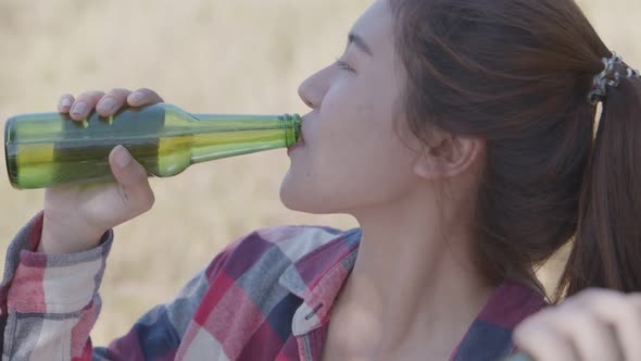 Asian woman happy with friends camping in nature having fun together drinking beer.