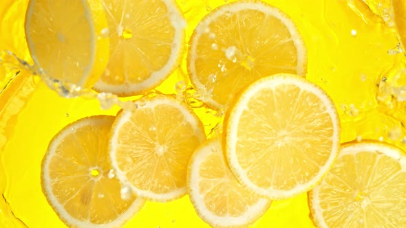 Super Slow Motion Shot of Lemon Slices Falling Into Water on Yellow Background at 1000Fps