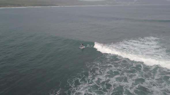 Paddleboarder attempts in vain to catch a small surf wave, aerial