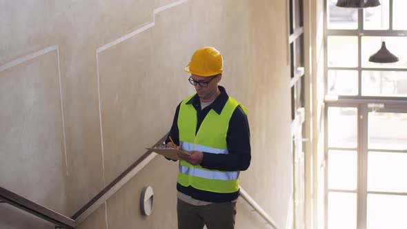 Builder in Helmet with Clipboard on Stairs