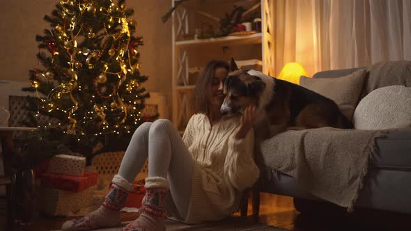 Beautiful Smiling Lovely Relaxed Woman and Her Nice Cute Welsh Corgi Dog Sitts at Couch at Winter