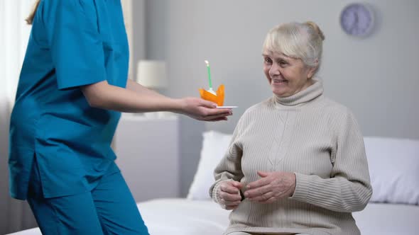 Kind Nurse Giving Birthday Cake to Aged Lonely Woman, Taking Care in Old Age