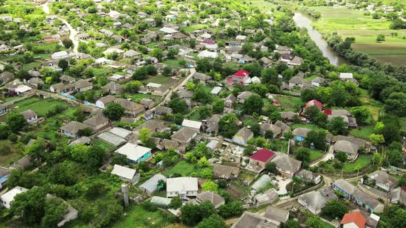 Aerial drone view of village in a valley in Moldova, multiple buildings, greenery, hills