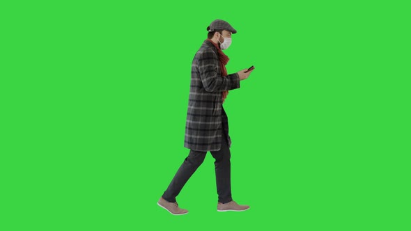 Adult Man Wears Protective Medical Mask Talking on the Phone and Walking on a Green Screen, Chroma