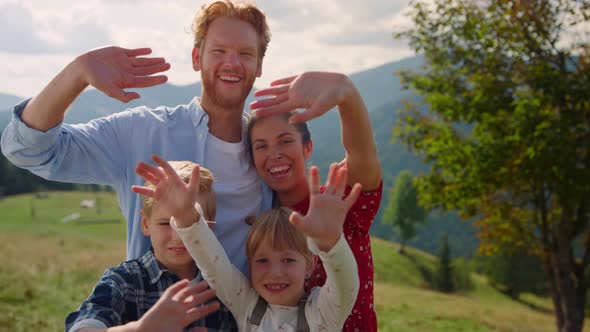 Cheerful Family Posing Camera on Green Mountains