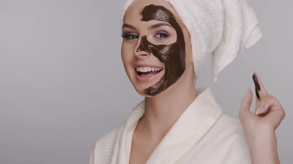 Happy Woman Applying Facial Clay Mask Isolated on Grey