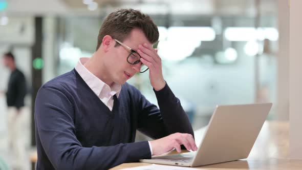 Stressed Young Businessman with Laptop Having Headache 