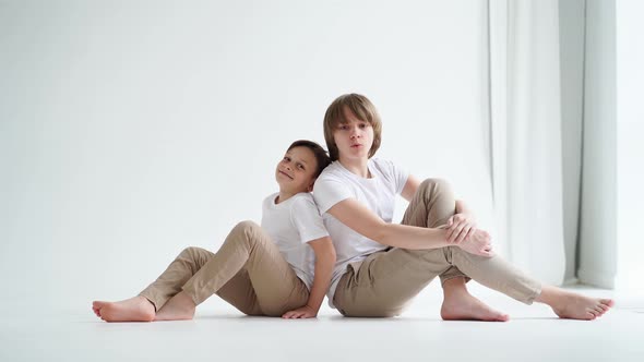 Two Boys in White Tshirts Pose for a Photographer in a Photo Studio