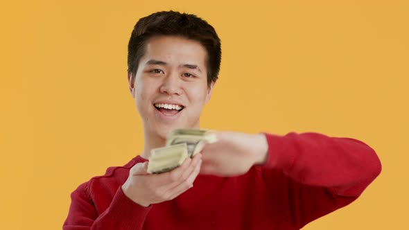 Rich Asian Guy Throwing Out Money Cash Over Yellow Background