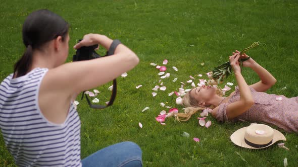 Photographer Takes Pictures of a Girl Lying a Beautiful Woman in a Green Meadow Who Holds a Bouquet