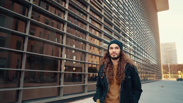 Portrait of Long Haired Hipster Walking on Street in Modern City