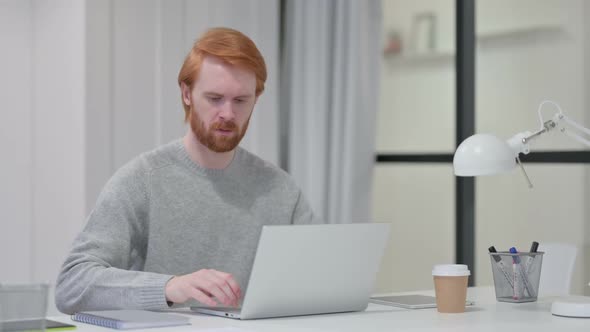Thumbs Down By Young Beard Redhead Man with Laptop