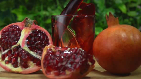 Red Juice Wave is Flowing Into a Small Glass on the Background of Greenery