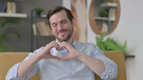 Portrait of Young Man Showing Heart Sign By Hand