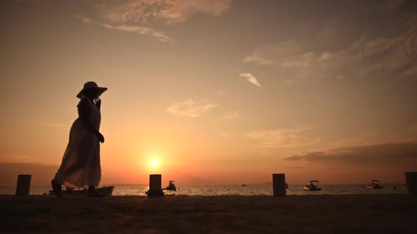 Woman in Large Sun Hat Walking Along Marina Shore