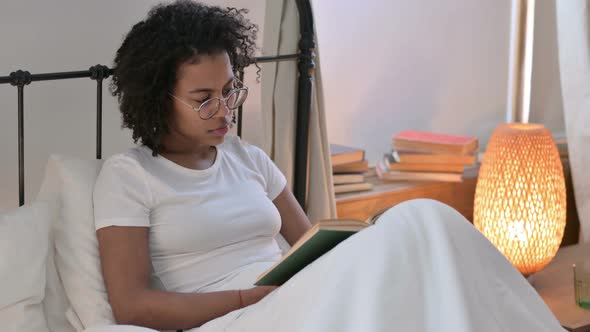 Beautiful Young African Woman Reading Book in Bed 