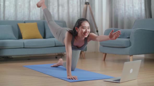 Asian Athletic Female Doing Yoga In Balancing Table Pose On The Mat At Home With Online Coach