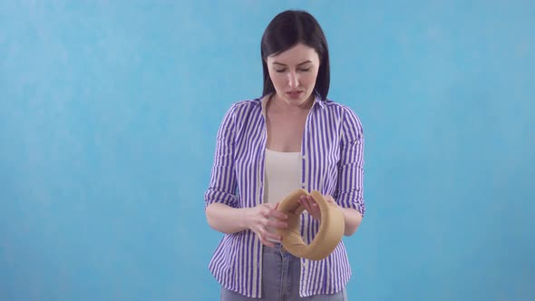 Young Woman Experiences Pain in Her Neck and Puts on a Protective Collar While Standing on a Blue