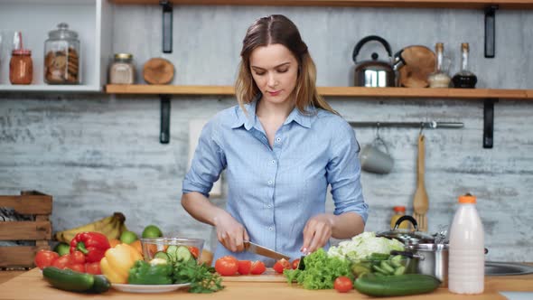 Smiling Beautiful Young Woman Cutting Fresh Organic Vegetable on Table