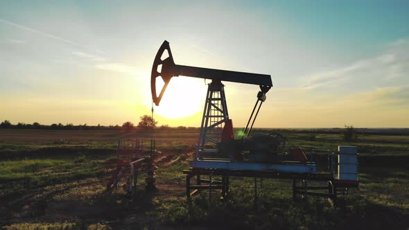 Silhouette Working Oil Pump in Deserted District at Sunset