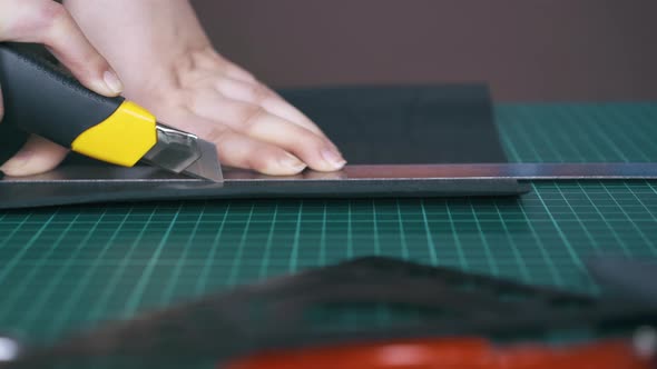 Careful Tailor Cuts Black Leather Cloth with Box Cutter