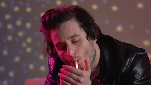 Young Male Lighting Up Cigarette, Relaxing at Party in Night Club, Close-Up