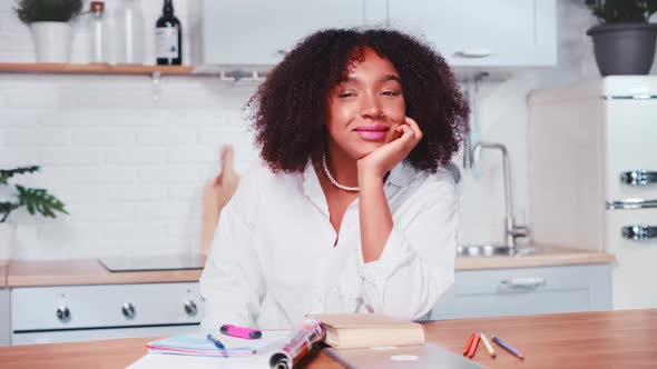 Smiling African American Woman with Curls Propping Head with Hand Look at Camera