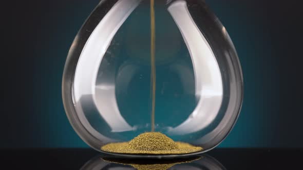 An Hourglass Made of Yellow Metal Shavings Passes Through a Funnel Symbolizing the Concept of Time