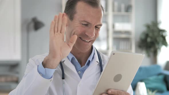 Senior Doctor Discussing with Patient via Video Chat on Tablet