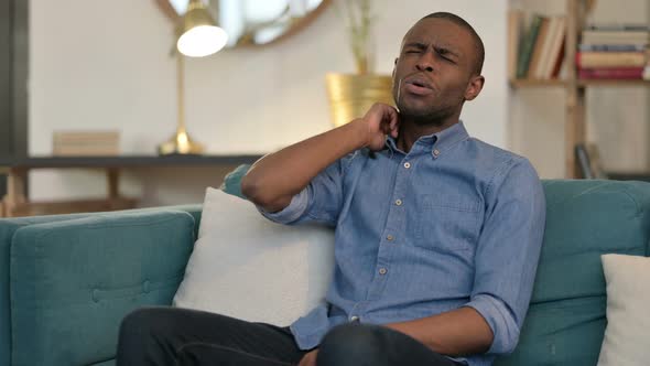 Exhausted Young African Man Having Neck Pain on Sofa 