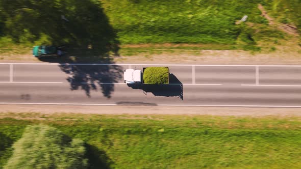 A Truck Loaded with Crushed Grass is Driving Along the Road Aerial View