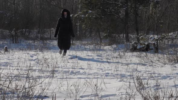 Young Woman in Winter Coat of Black Colour Runs Along Snow