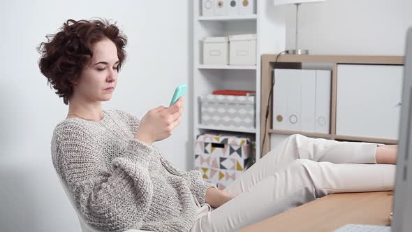 Young Woman Procrastinates Scrolling her Smartphone