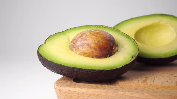 Avocado halves with seed close up on a wooden cutting board