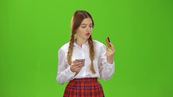 Girl Dials Numbers on the Phone with a Gold Card. Green Screen