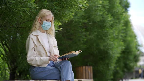 A Student Wearing a Medical Mask Reads a Book in the Park