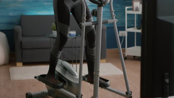 Fit Slim Woman Trainer Wearing Sportswear Training Body Muscles Working on Elliptical Bike